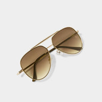 Top-down flat lay of folded Bali sunglasses with gold frame and brown lenses