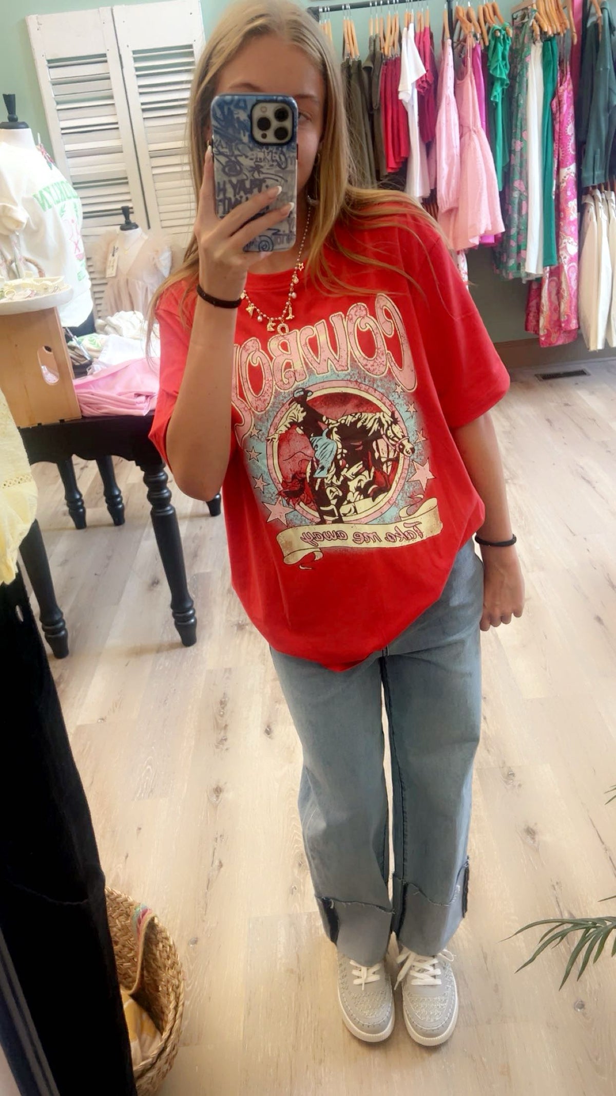 Stylish woman wearing the Cowboy Take Me Away Graphic Western Loose Tee for Women in vibrant tomato red.