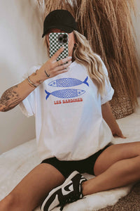 Model wearing an oversized tee with a colorful sardine can graphic on the front.