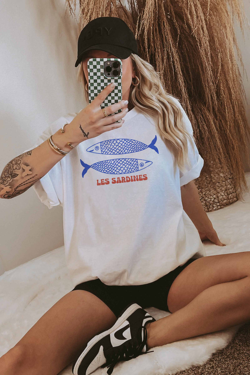 Model wearing an oversized tee with a colorful sardine can graphic on the front.