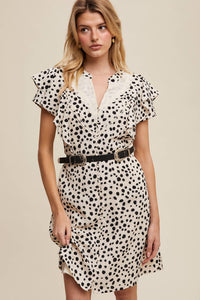 Front view of model wearing ruffled polka dot dress with lace neckline and belted waist styling