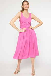 Model wearing a pink midi dress with twist detail at the bust, fully lined, made of 100% polyester, standing against a white background.